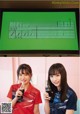 A couple of women standing next to each other in front of a television.