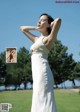 A woman in a white dress standing in a field.