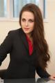 A woman in a black suit sitting at a desk.