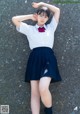 A woman in a school uniform laying on the ground.