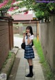 A woman in a school uniform eating a piece of food.