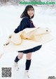 A woman in a school uniform is walking in the snow.