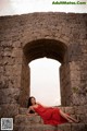 A woman in a red dress sitting on some steps.