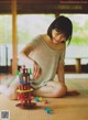 A woman sitting on the floor playing with a toy tower.