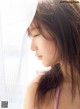 A woman with long brown hair looking out of a window.