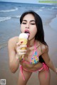 A woman in a bikini eating an ice cream cone.