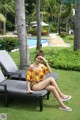 A woman sitting on a lounge chair next to a swimming pool.