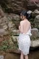 A woman in a white dress standing in a stream.