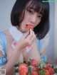 A woman in a blue dress eating a strawberry.