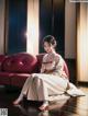 A woman in a white kimono sitting on a red couch.