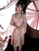 A woman in a pink kimono standing in front of a window.