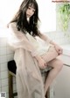 A woman sitting on a stool in a bathroom.