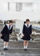 Two young women in school uniforms standing on a roof.